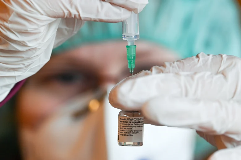Medizinische Fachkraft zieht Spritze mit Impftstoff auf