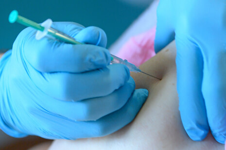 Detailaufnahme: Eine Coronaschutzimpfung wird in den Oberarm gespritzt