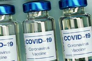 3 Flaschen mit Covid-Impfstoff liegen nebeneinander